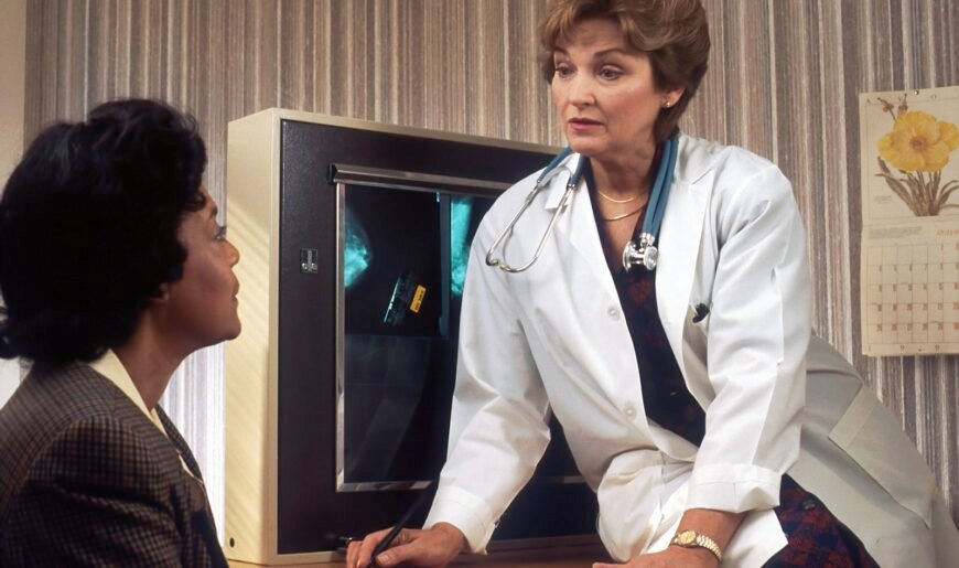 Une patiente échange avec un médecin assis à son bureau lors d'une consultation
