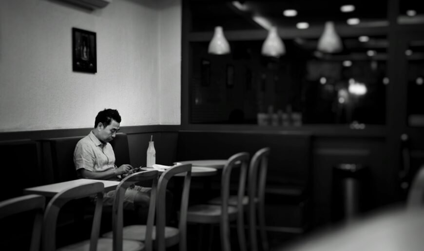 Homme assis seul dans un café, regardant son smartphone en attendant une réponse