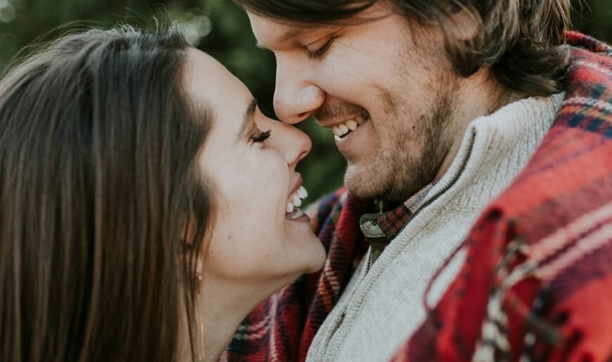Un homme et une femme emmitouflés rient ensemble en extérieur par une journée froide d'automne