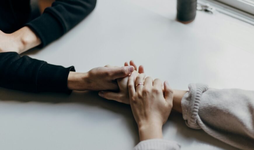Deux personnes en couple se tenant la main sur une table blanche