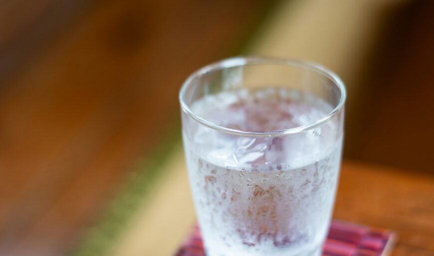 Verre d'eau posé sur une table en bois, rappel de l'hydratation pour prévenir la cystite