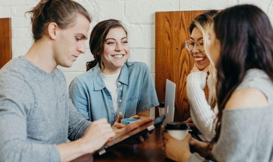 Groupe d'amis adultes qui discutent autour d'une table dans un café
