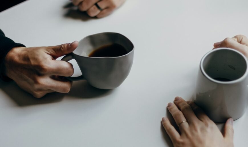 Deux personnes assises à une table de café avec des tasses, lors d'un premier rendez-vous dans un lieu public
