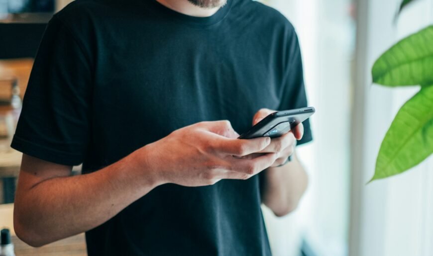 Un homme tient un smartphone à deux mains, prêt à écrire un premier message sur une application de rencontre